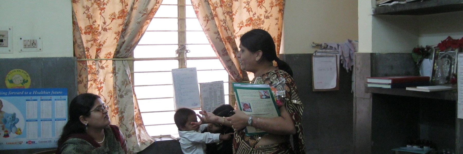 A health worker going through a leaflet with a mother and her toddler
