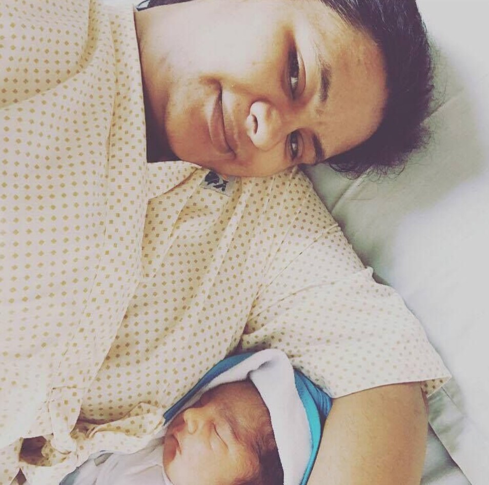 A mother resting beside her newborn on the ward