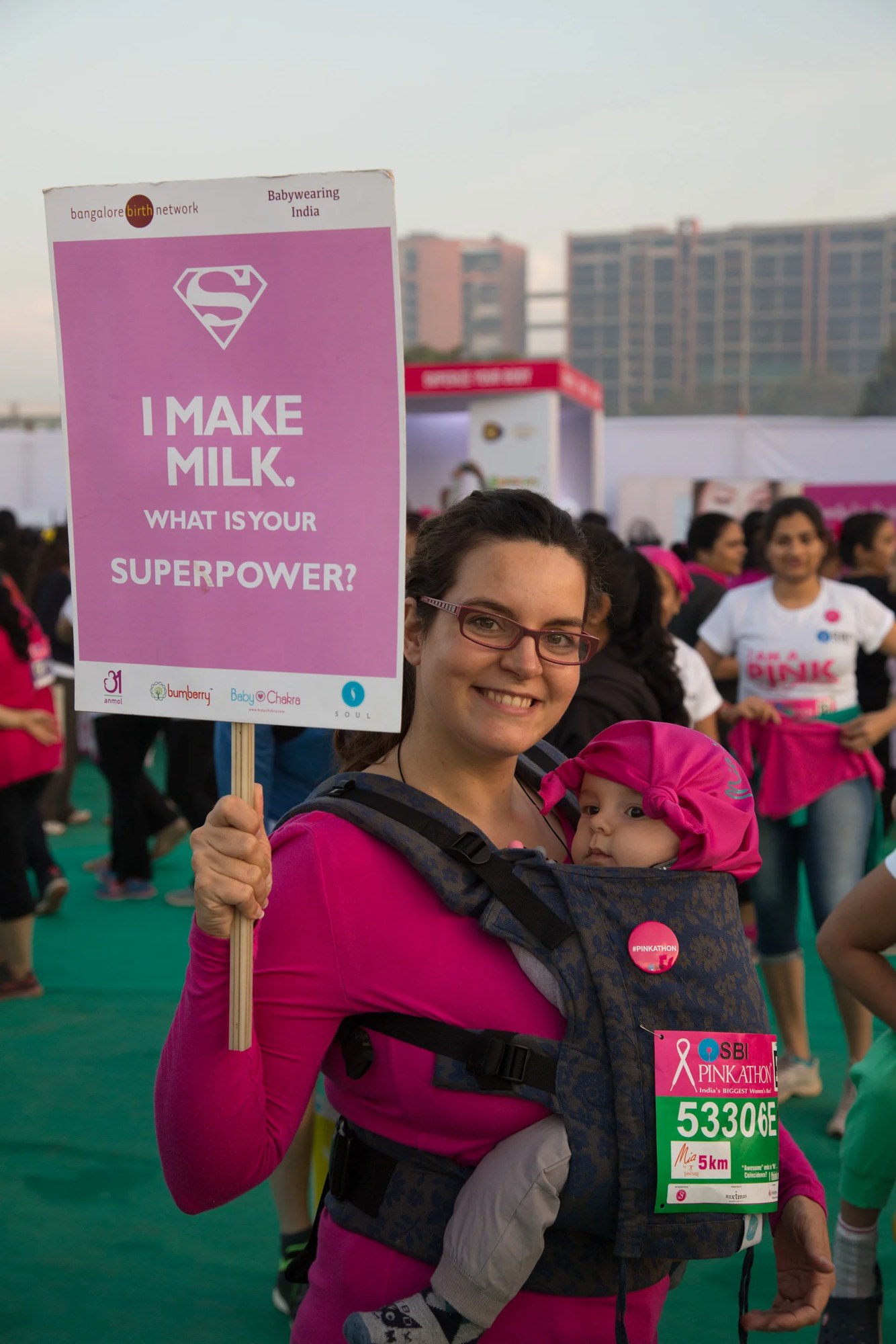 A mother holding an 'I make milk, what's your superpower' placard